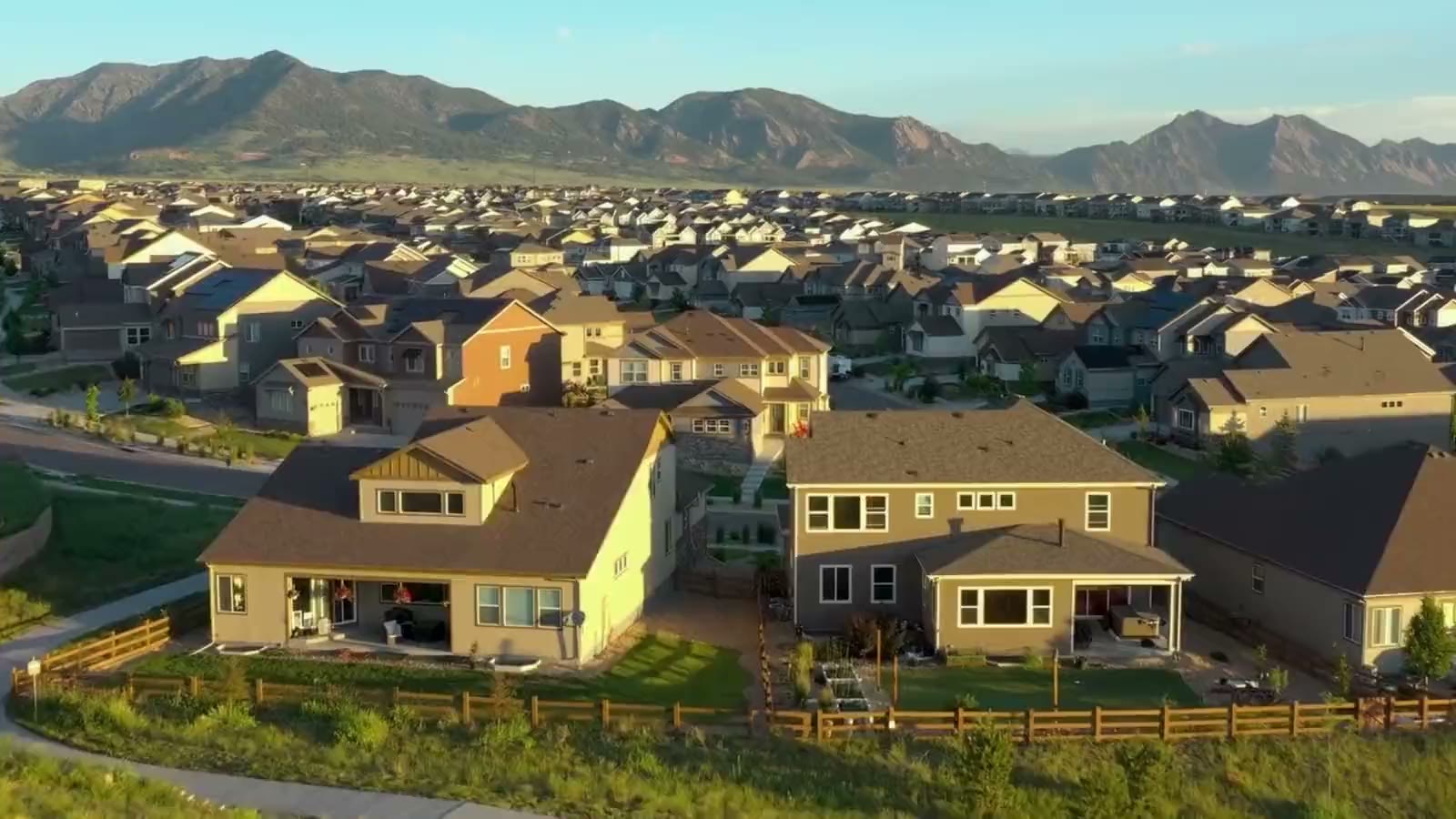 Aerial view of a Front Range neighborhood at golden hour with the foothills beyond